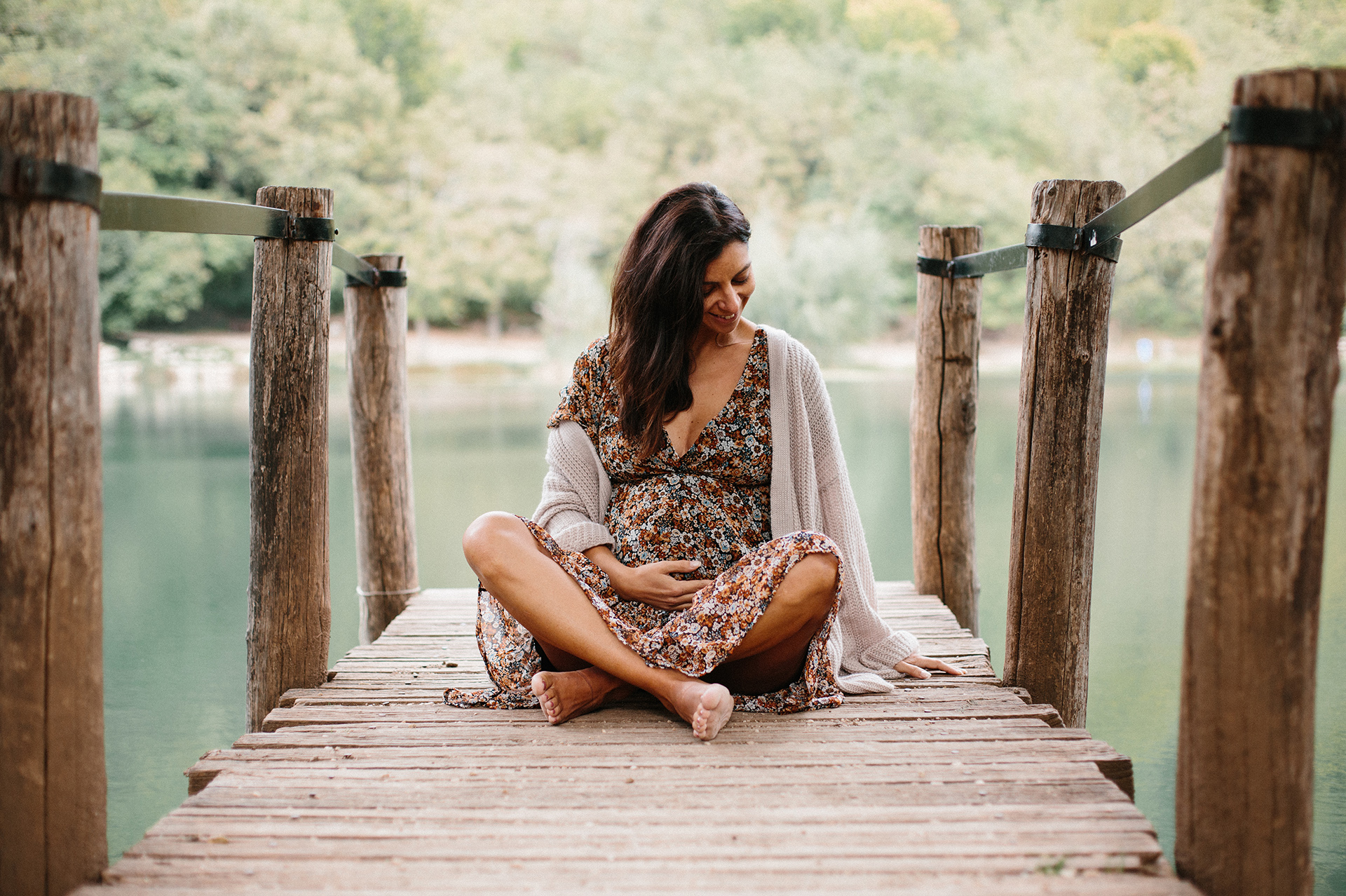 donna incinta seduta su un molo al lago
