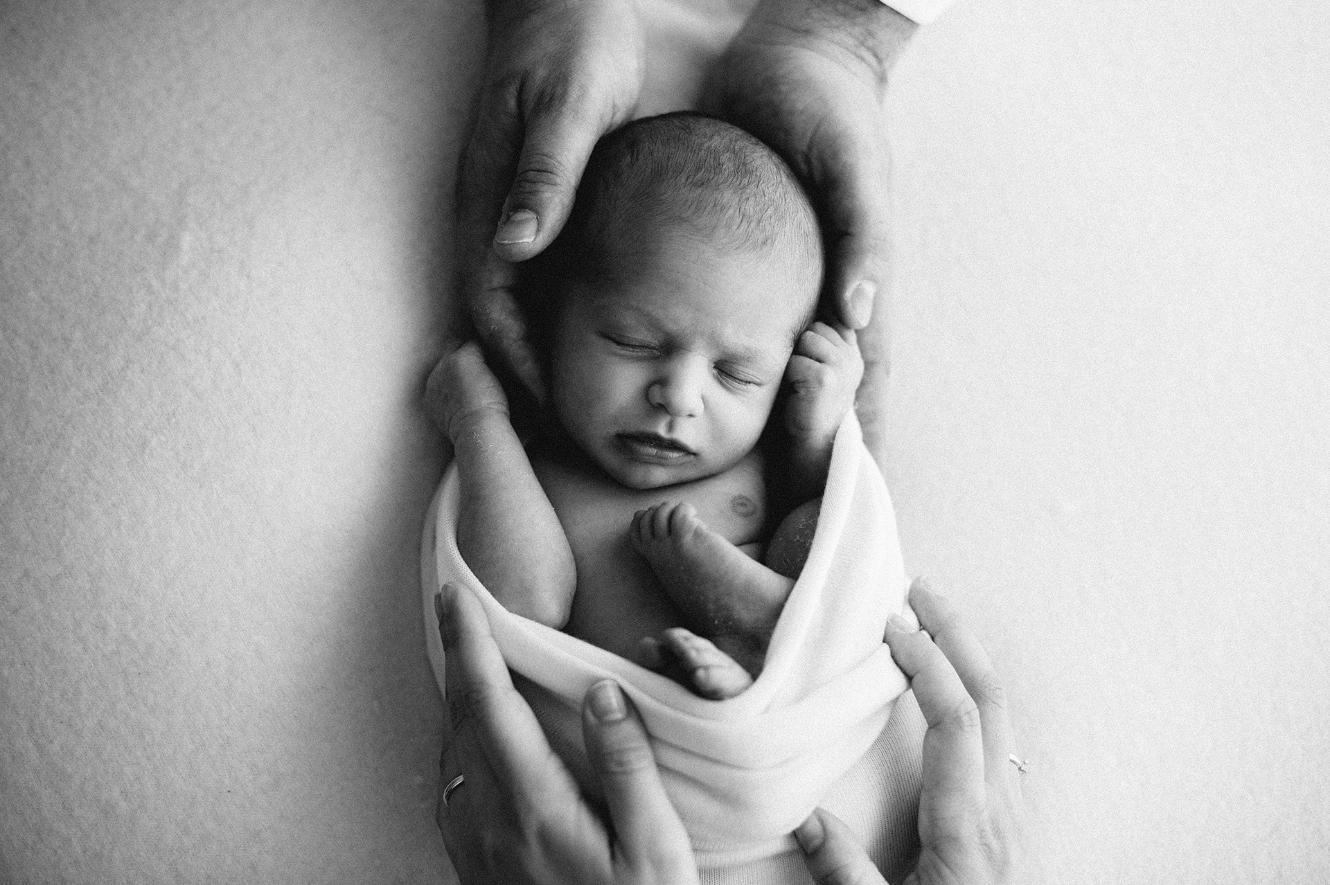 le mani dei genitori circondano il neonato