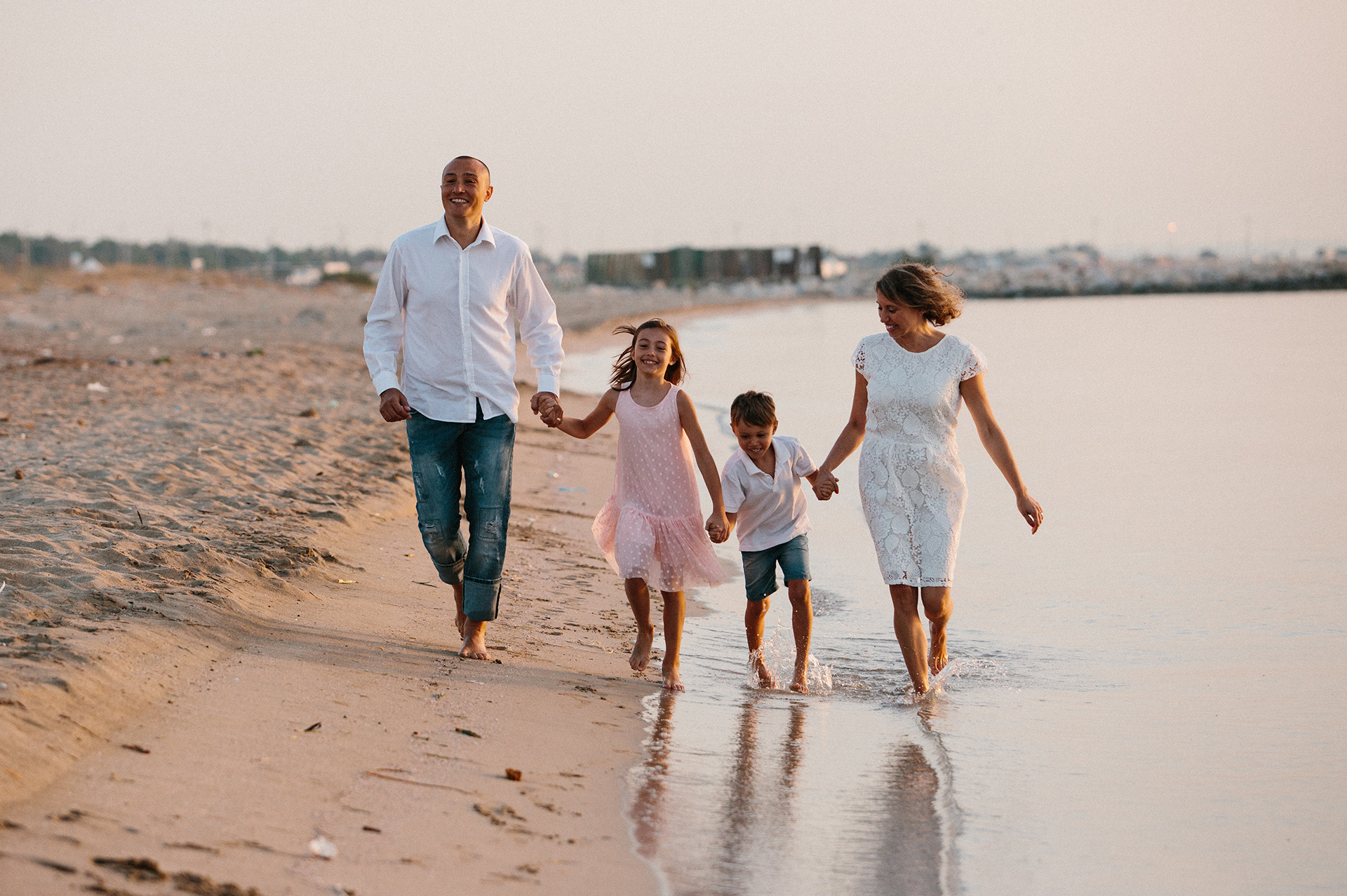 famiglia con due bambini cammina in riva al mare