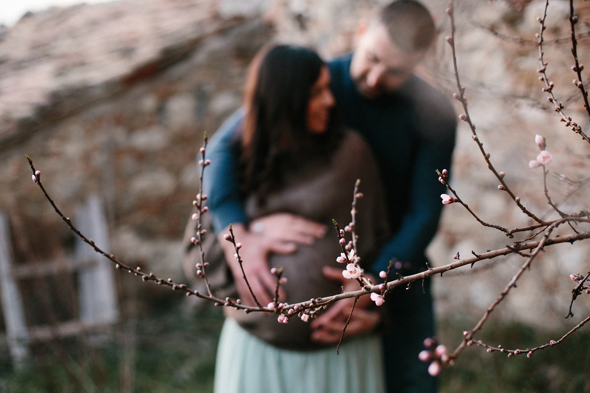 papà tiene le mani sul pancione della mamma al parco